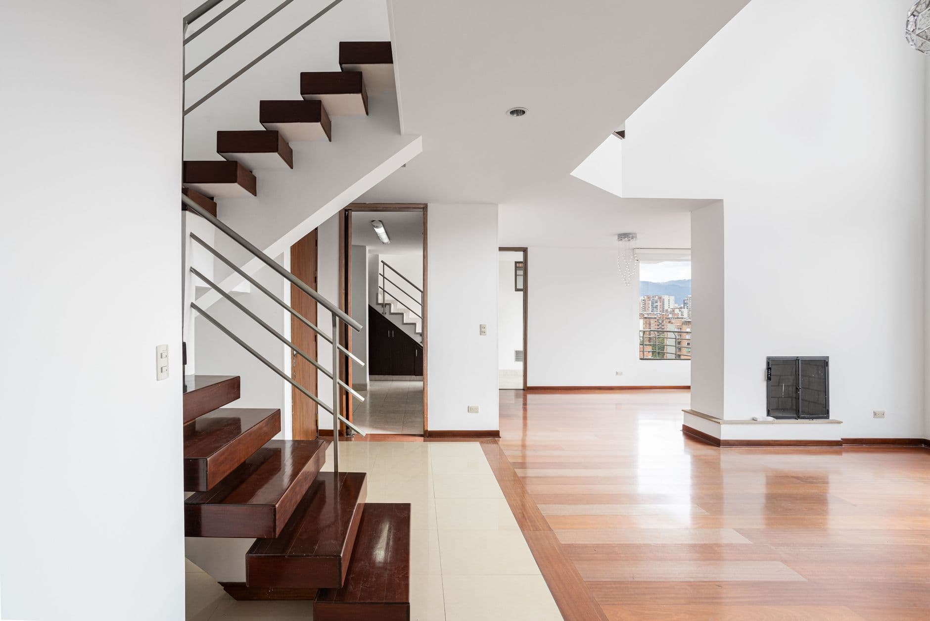 A modern and spacious apartment interior featuring wooden stairs and elegant design in Bogotá, Colombia.