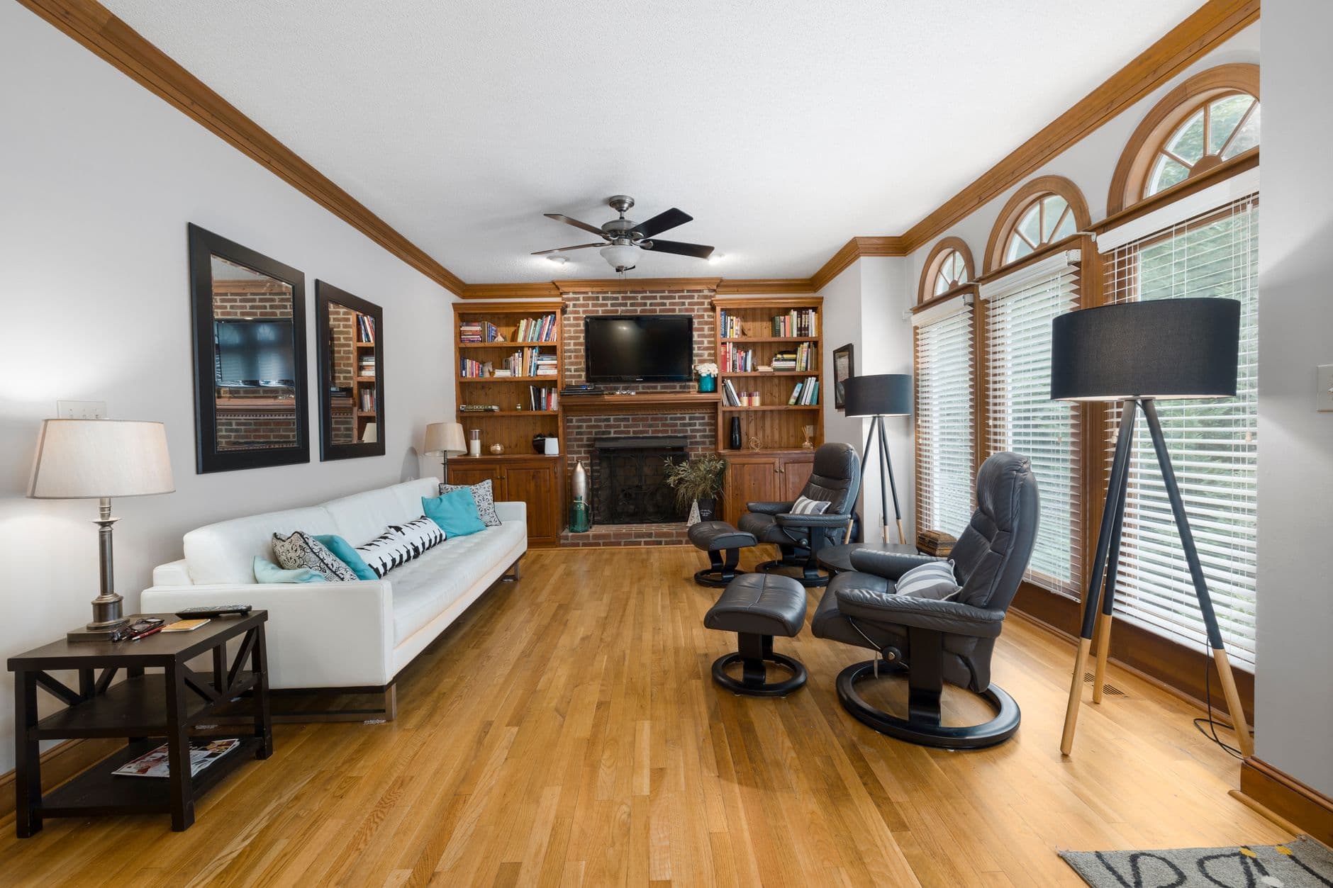 Elegant living room with chic decor, featuring a couch, armchair, and fireplace in a bright space.