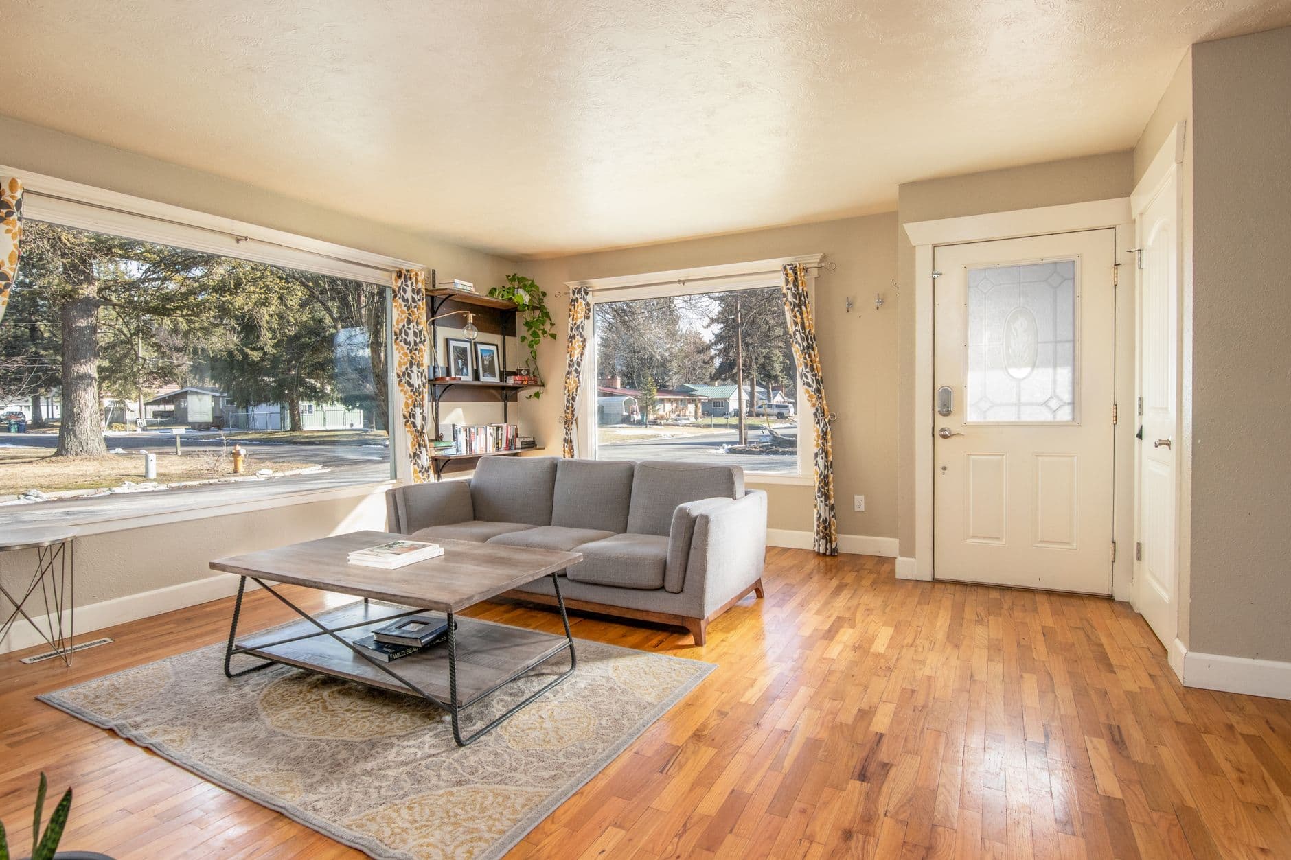 Cozy modern living room with bright sunlight through large windows.