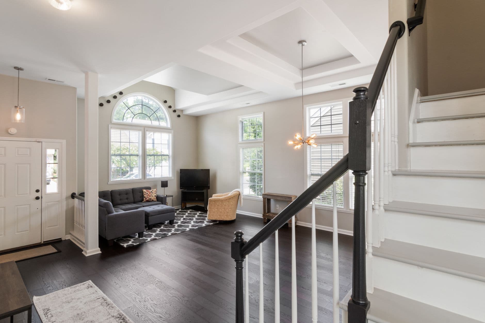 Bright and spacious contemporary living room with elegant staircase and modern furniture.