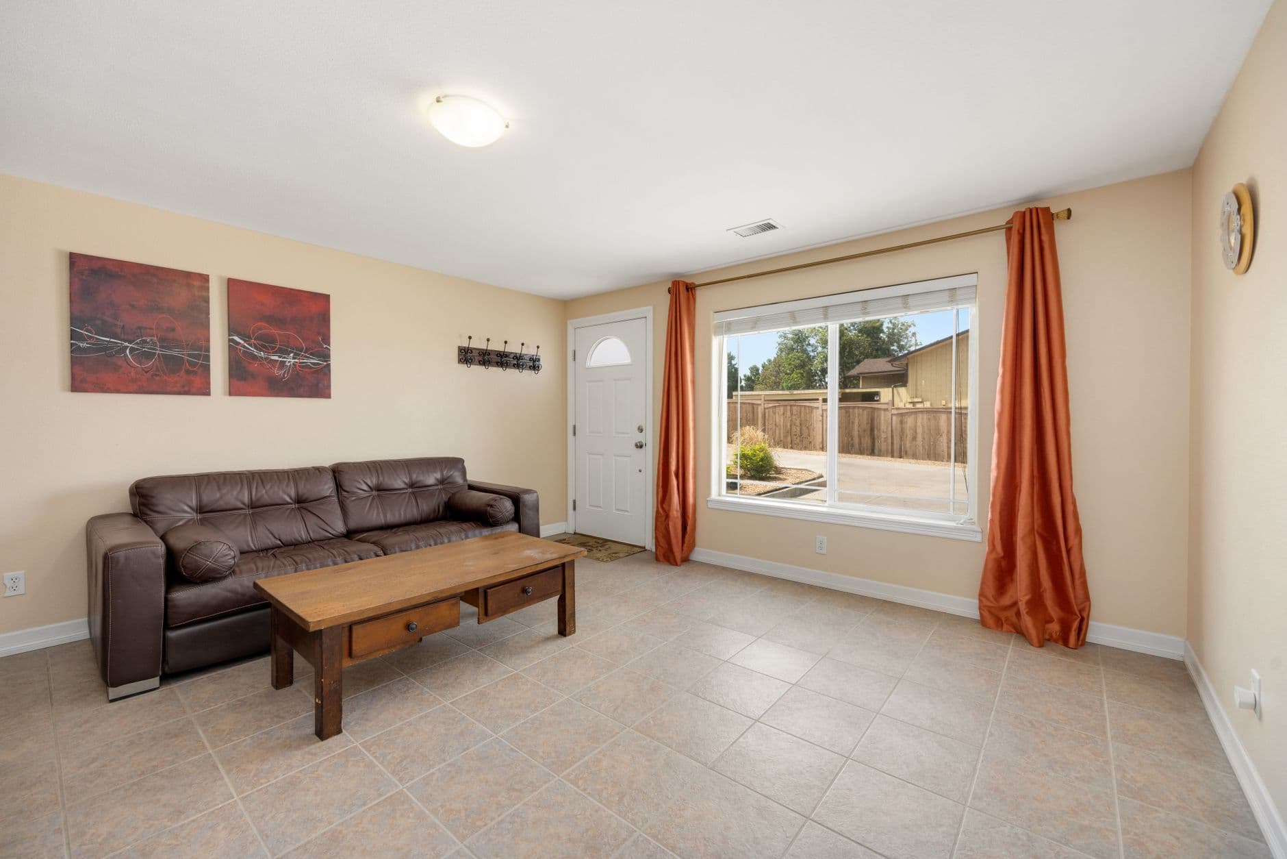 Bright living room with leather sofa, wooden coffee table, and large window view.