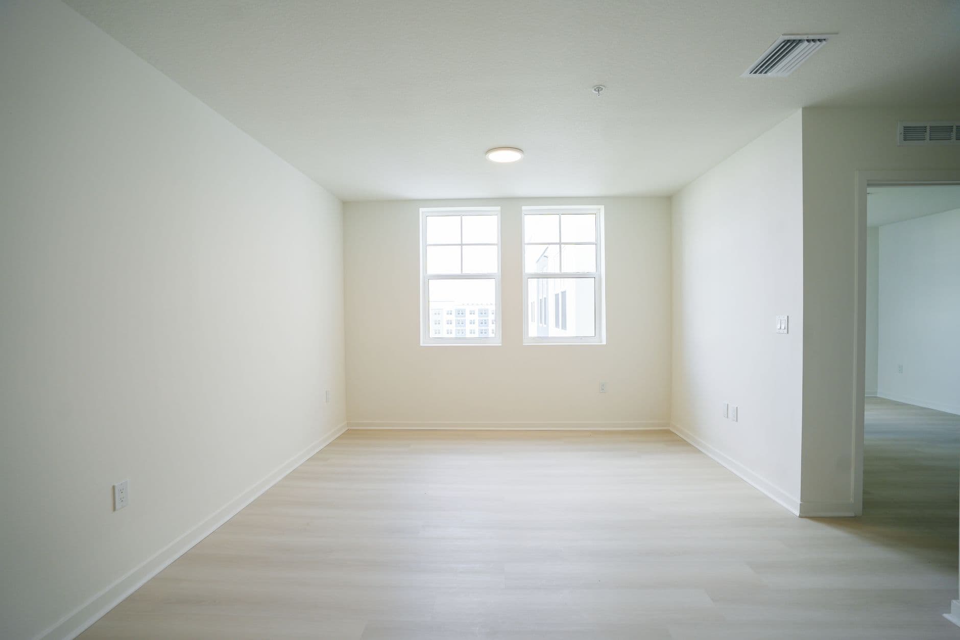 Minimalist empty room with bright natural light and hardwood floors, ideal for real estate listings.