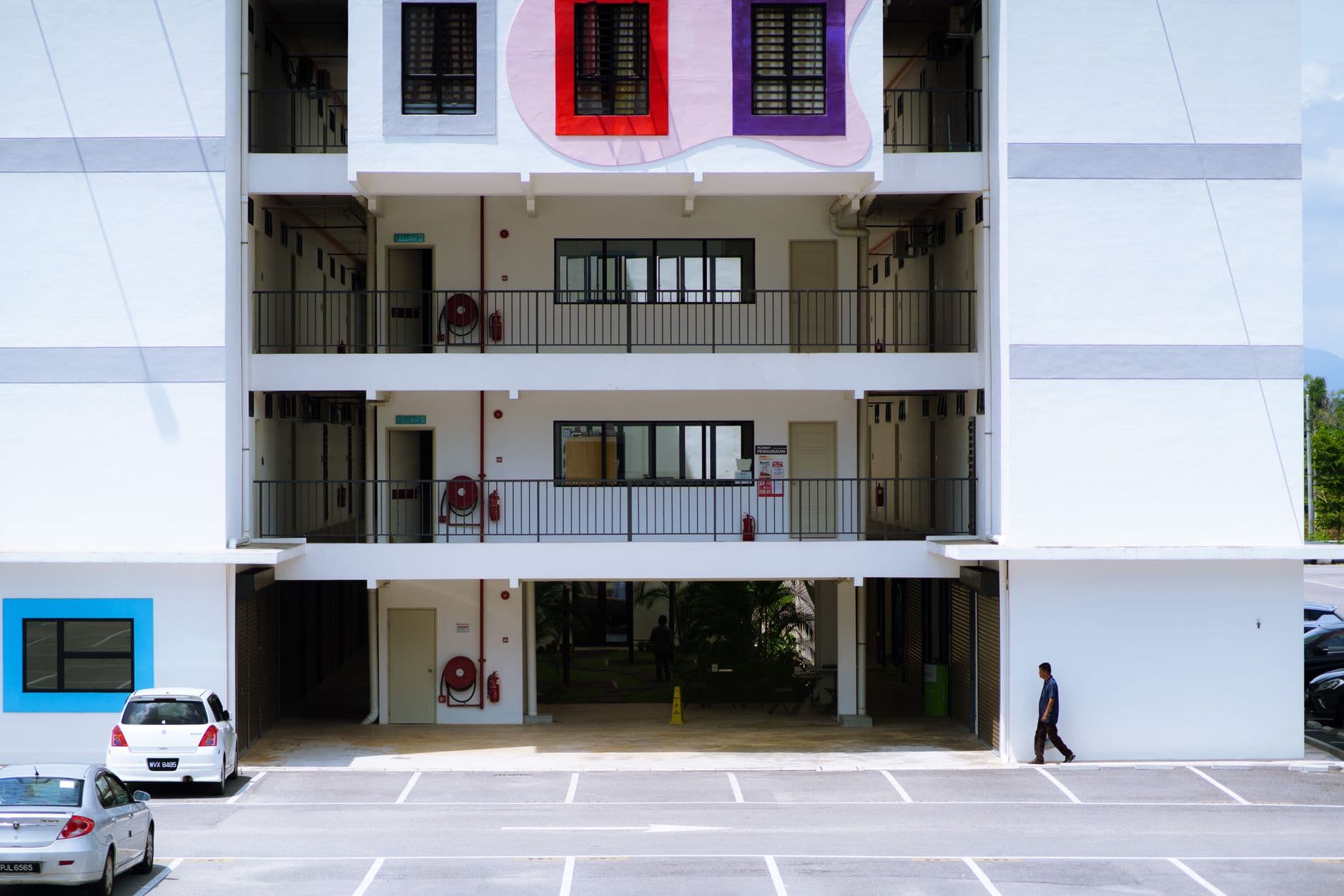 Contemporary apartment building exterior with geometric wall art and empty parking lot.