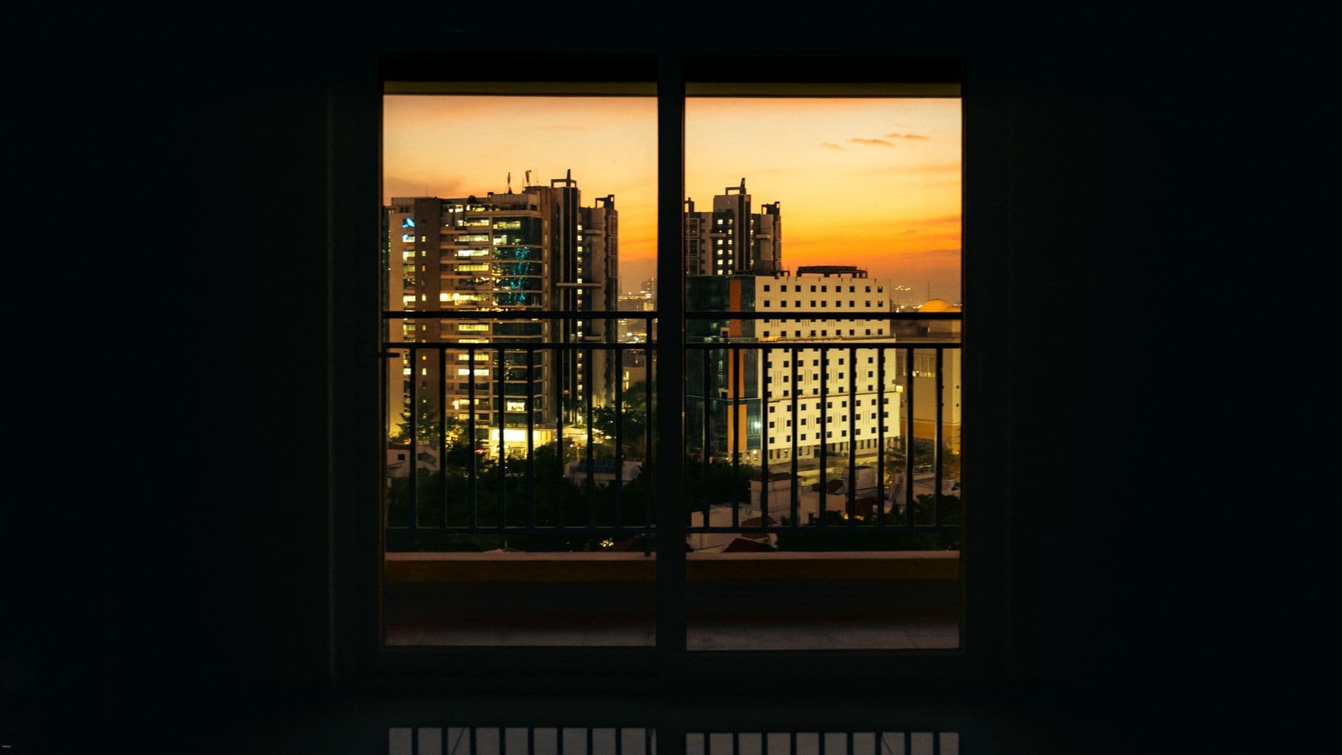 Cityscape view of Hyderabad at sunset through a balcony window, showcasing the vibrant skyline.
