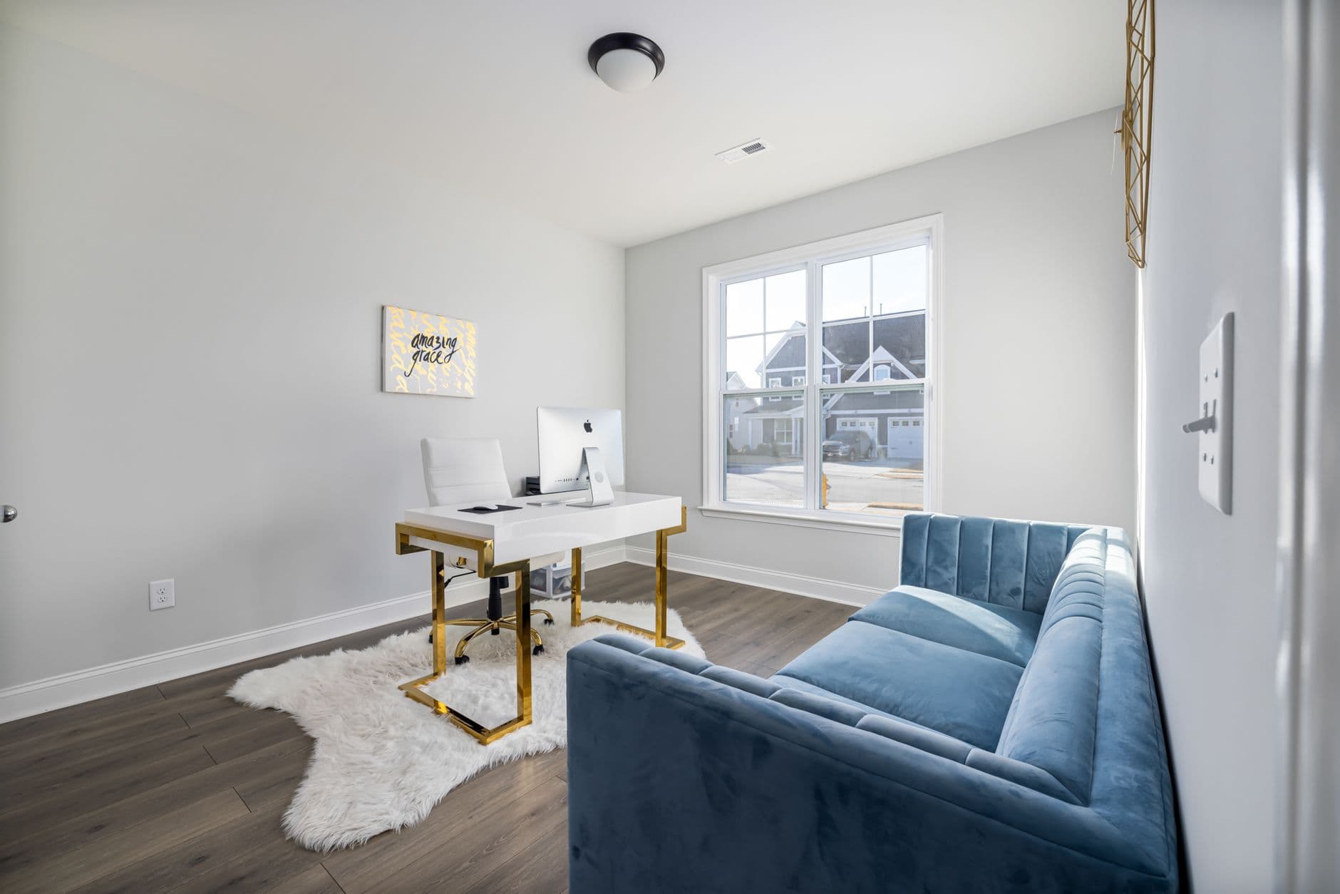 A stylish modern home office featuring a velvet couch and sleek desk with natural light.