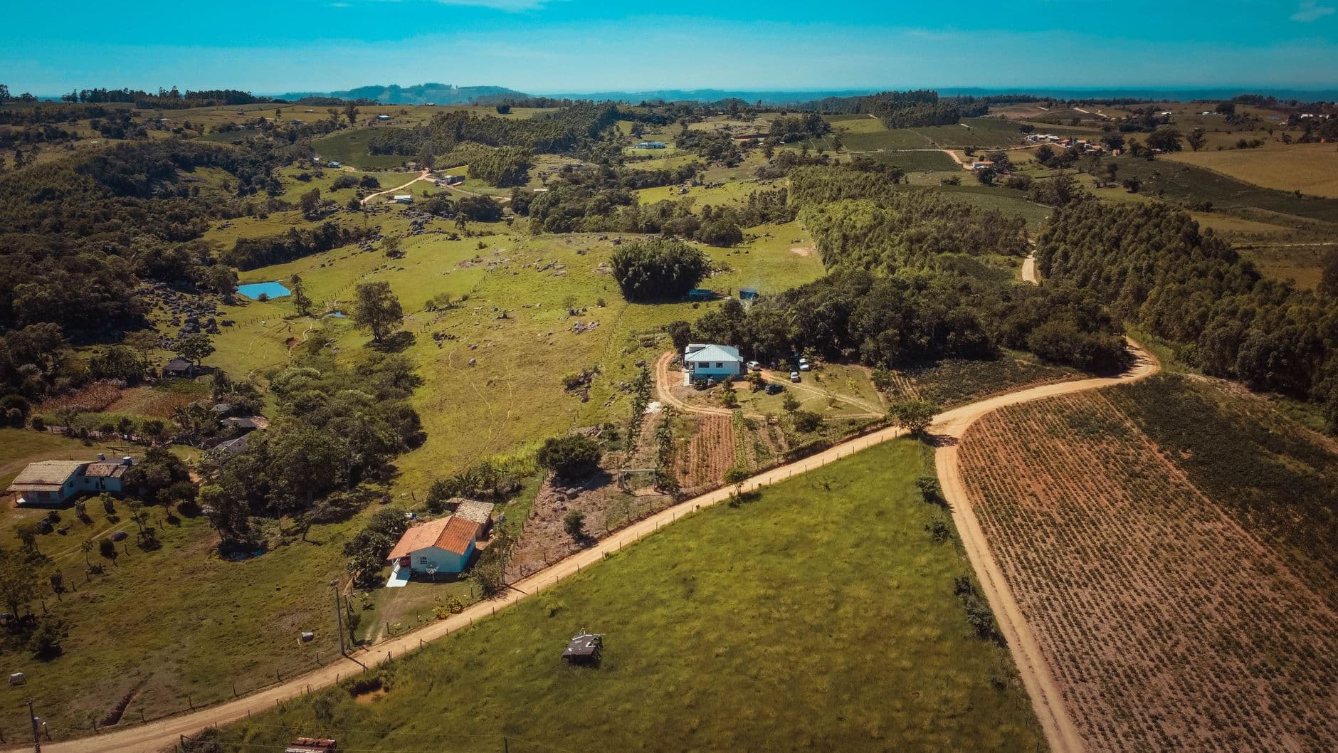 Scenic aerial view of rolling rural landscape in Tubarão, Brazil with croplands and houses.